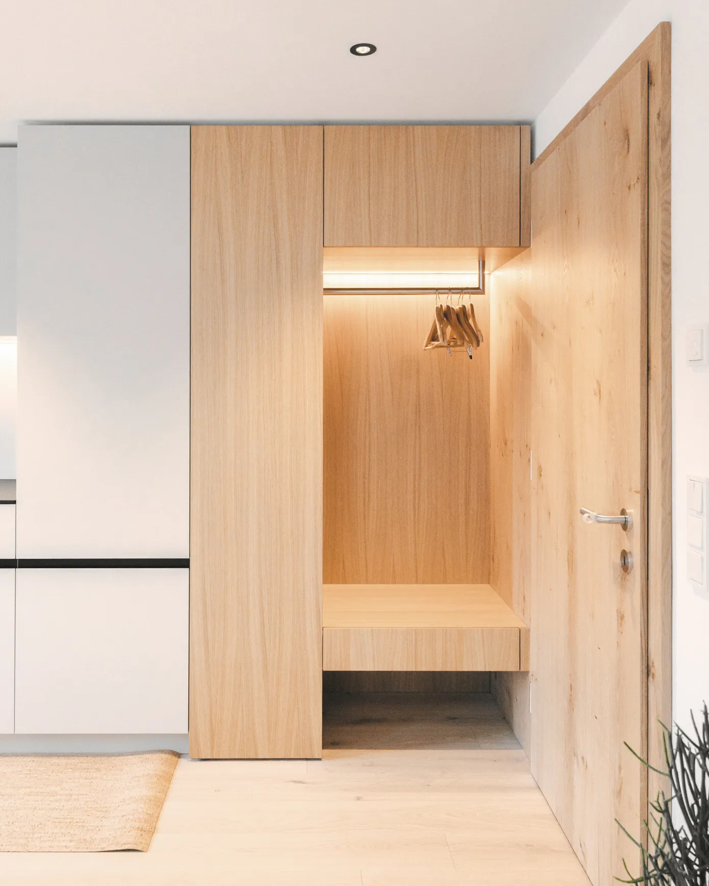 Moderner und funktionaler Eingangsbereich im Aparthotel Hubertus in Mellau – mit integrierter Garderobe aus hellem Holz, Sitzbank und Hängemöglichkeit für Kleidung, ideal für eine geordnete Ankunft im Bregenzerwald.