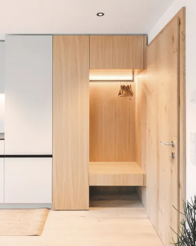 Moderner und funktionaler Eingangsbereich im Aparthotel Hubertus in Mellau – mit integrierter Garderobe aus hellem Holz, Sitzbank und Hängemöglichkeit für Kleidung, ideal für eine geordnete Ankunft im Bregenzerwald.